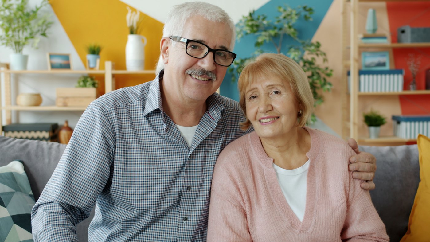 An older couple smiling together on their sofa at home